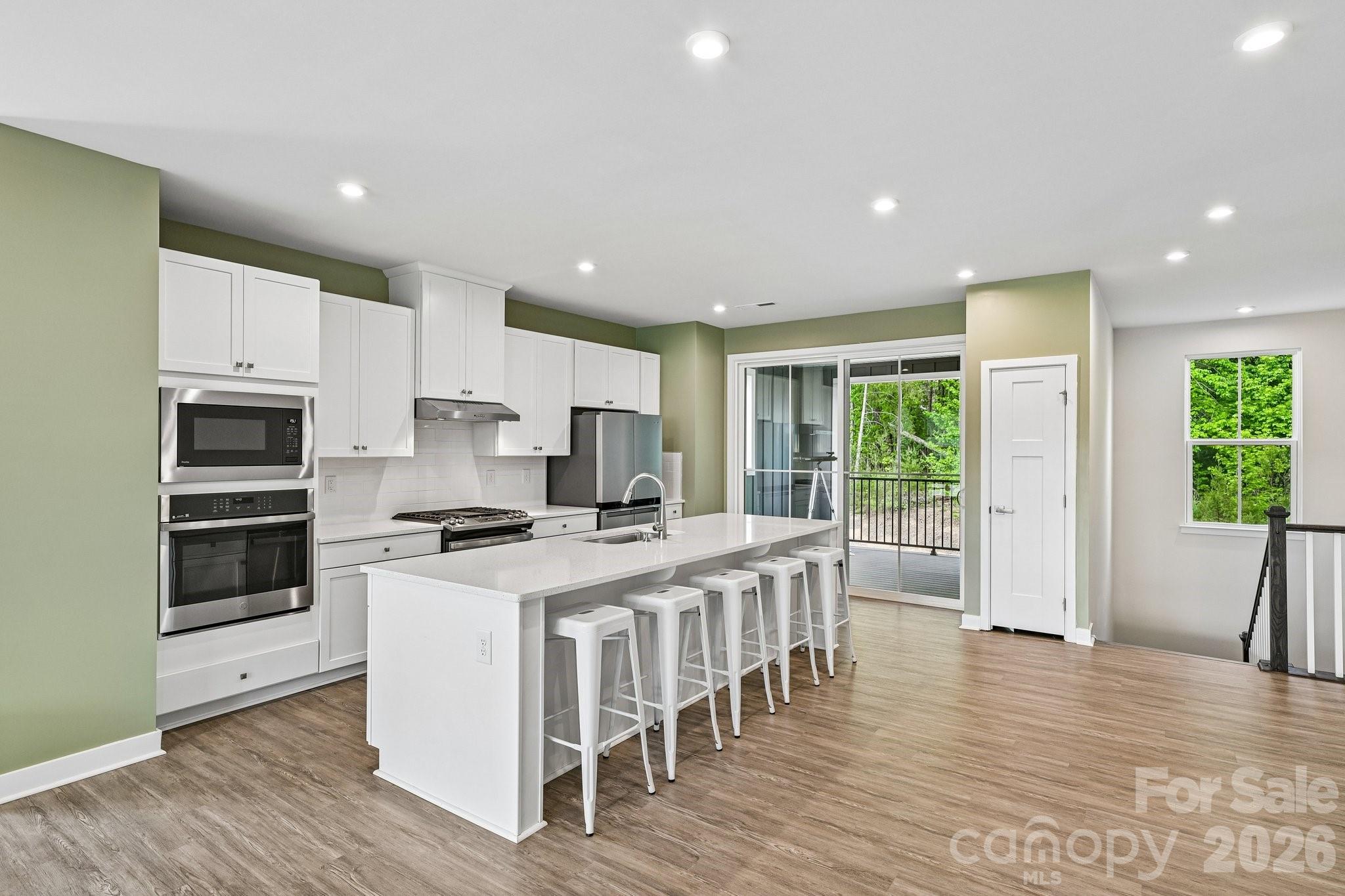 957 Portrush Lane Tega Cay, SC 29708 - Photo 8 of 39 a kitchen with stainless steel appliances granite countertop a stove top oven a refrigerator a sink and a dining table with wooden floor