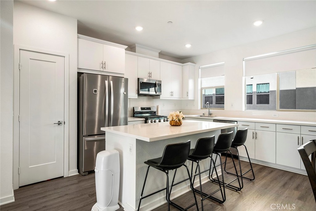 a kitchen with stainless steel appliances a table chairs refrigerator and cabinets