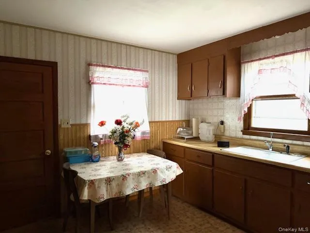 a kitchen with a sink a window and chairs