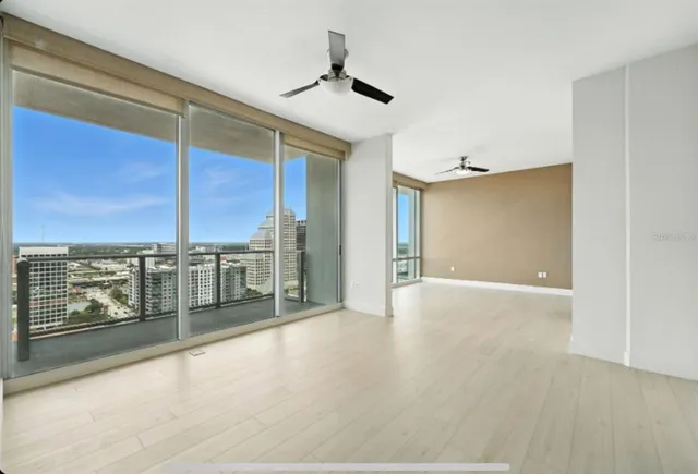a view of an empty room with wooden floor and a window