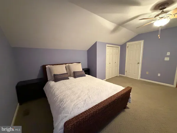 a spacious bedroom with a bed and a lamp on table