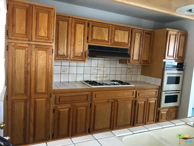a kitchen with granite countertop wooden cabinets and a stove top oven