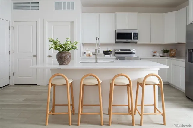 a kitchen with stainless steel appliances granite countertop a dining table cabinets and a potted plant