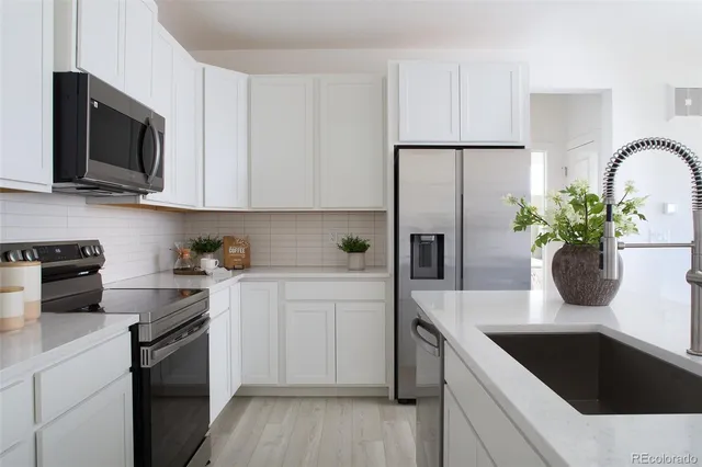 a kitchen with stainless steel appliances white cabinets a sink a stove and a microwave