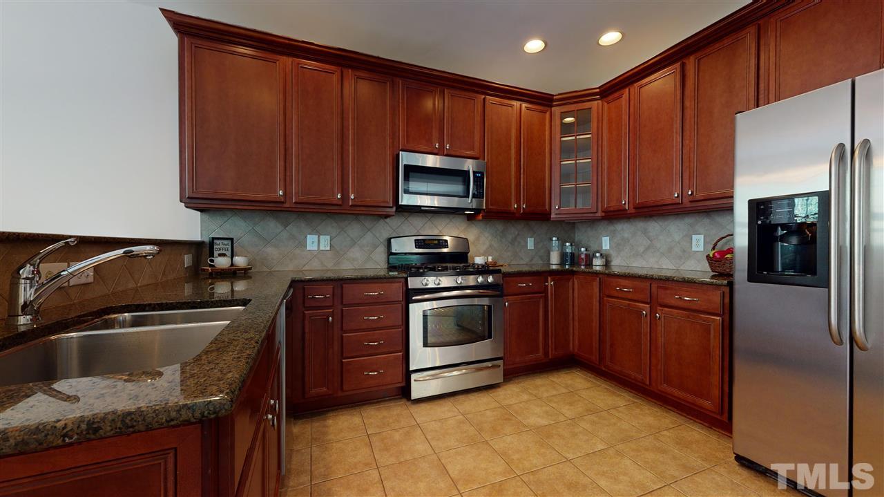 11245 Maplecroft Court Raleigh, NC 27617 - Photo 4 of 30 Chef’s kitchen feat. 42’ cherry cabinets, granite counters, tile backsplash, SS appliances, & gas range!