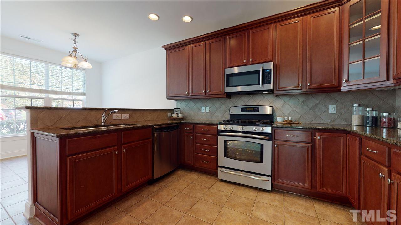 11245 Maplecroft Court Raleigh, NC 27617 - Photo 6 of 30 Chef’s kitchen feat. 42’ cherry cabinets, granite counters, tile backsplash, SS appliances, & gas range!