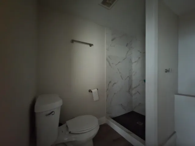 a bathroom with a granite countertop toilet and a shower