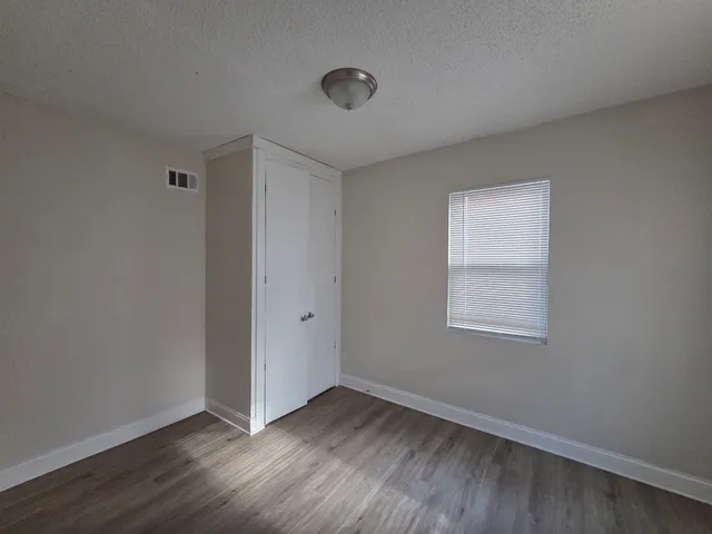 an empty room with wooden floor and windows