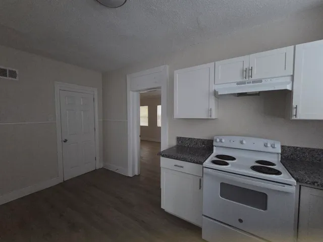 a kitchen with granite countertop white cabinets and white appliances
