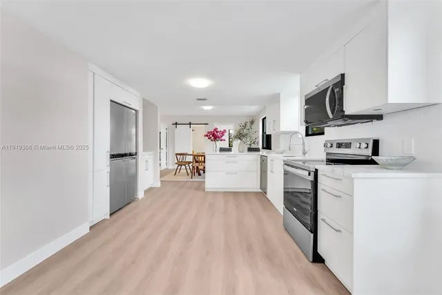 a kitchen with stainless steel appliances granite countertop a refrigerator sink and white cabinets