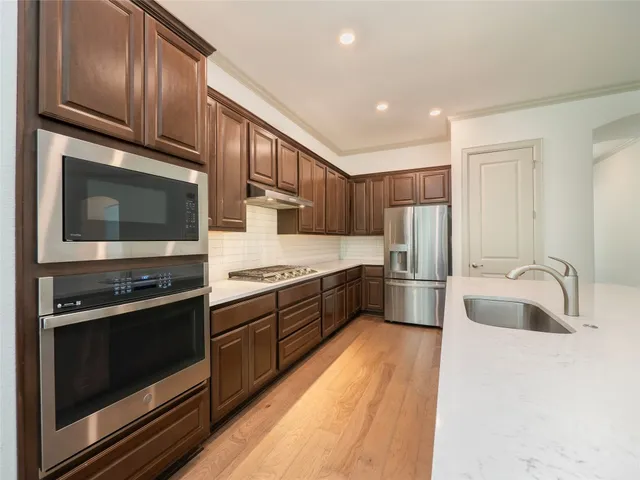 a kitchen with stainless steel appliances wooden cabinets a stove a microwave and wooden floors
