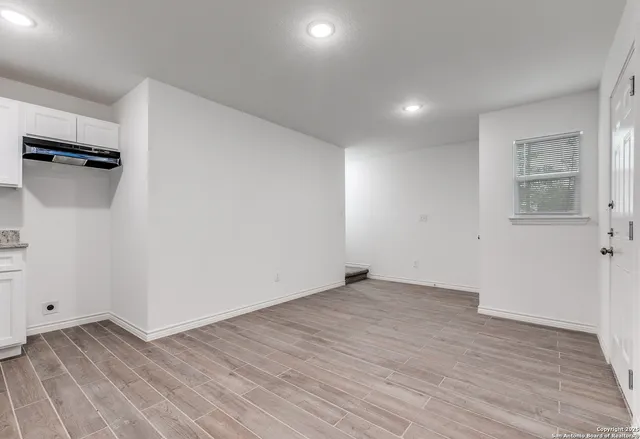 an empty room with wooden floor and a ceiling fan