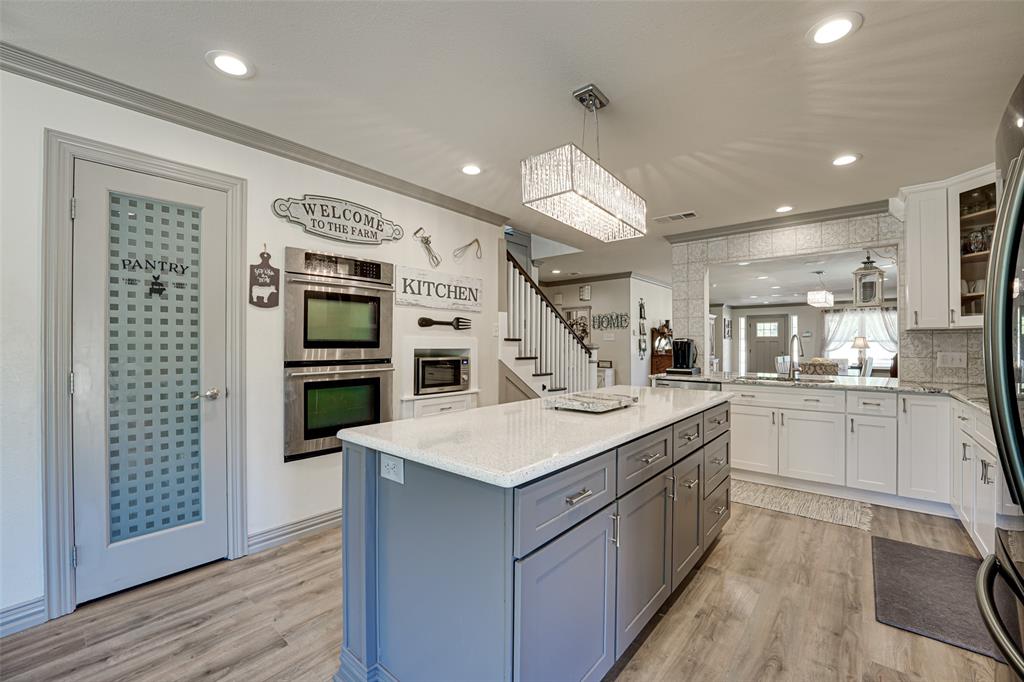 521 Bakers Branch Road Waxahachie, TX 75167 - Photo 18 of 37 Kitchen featuring a large central island with light-toned cabinetry, stainless steel double wall ovens, wood-finish flooring, and recessed lighting