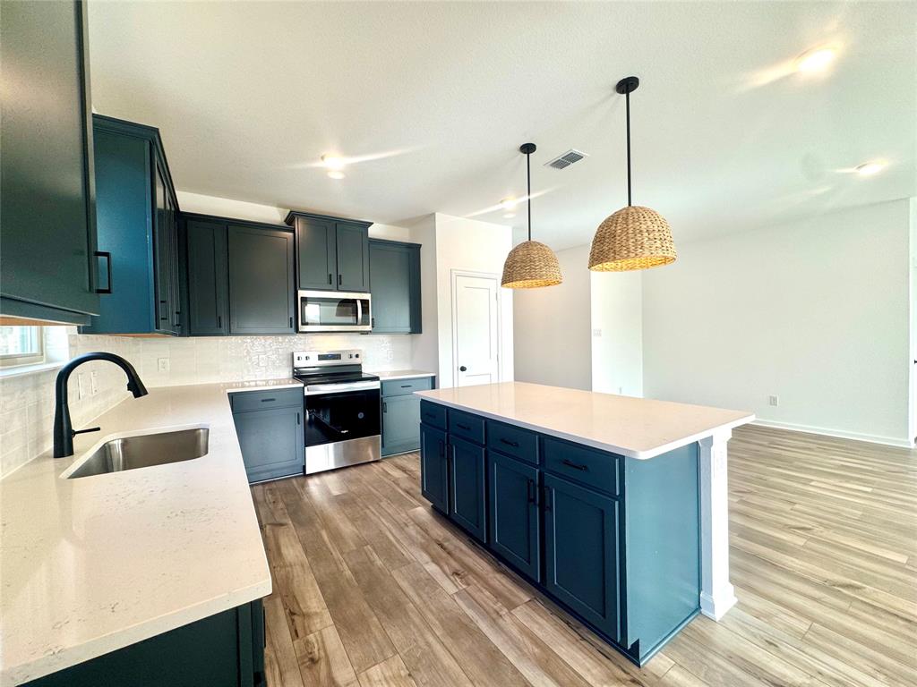 3113 Harmony Way Cleburne, TX 76031 - Photo 1 of 1 a kitchen with stainless steel appliances kitchen island a refrigerator a sink dishwasher a oven with wooden cabinets and wooden floor
