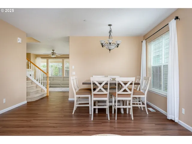 a dining room with wooden floor a chandelier a glass table and chairs