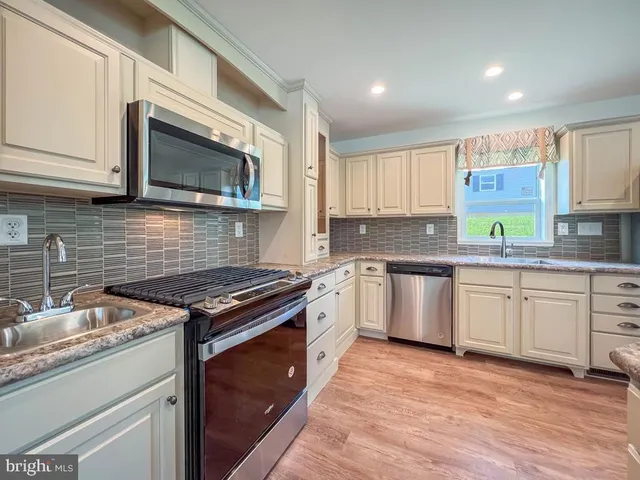 a kitchen with stainless steel appliances granite countertop wooden cabinets stove top oven and sink