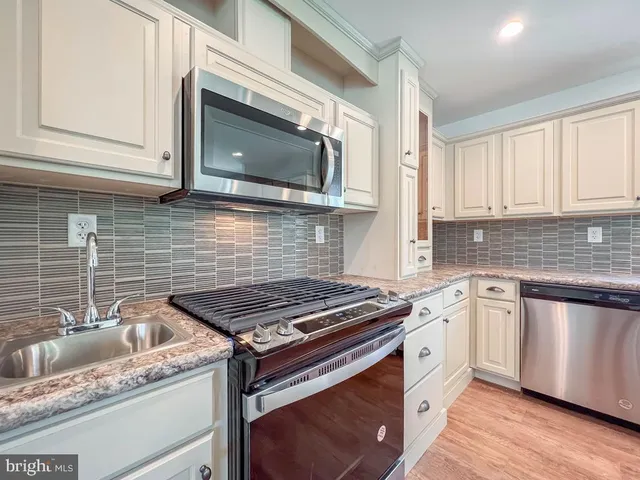 a kitchen with stainless steel appliances granite countertop a sink stove and microwave