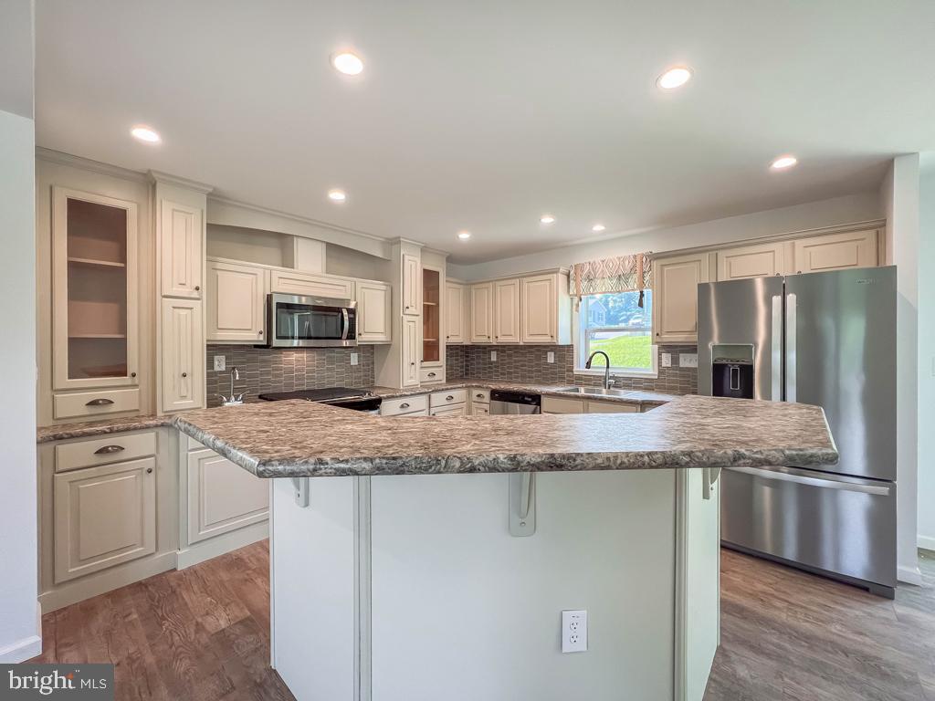146 Minch Road Parkesburg, PA 19365 - Photo 16 of 44 a large kitchen with stainless steel appliances granite countertop a stove a sink a refrigerator and white cabinets with wooden floor