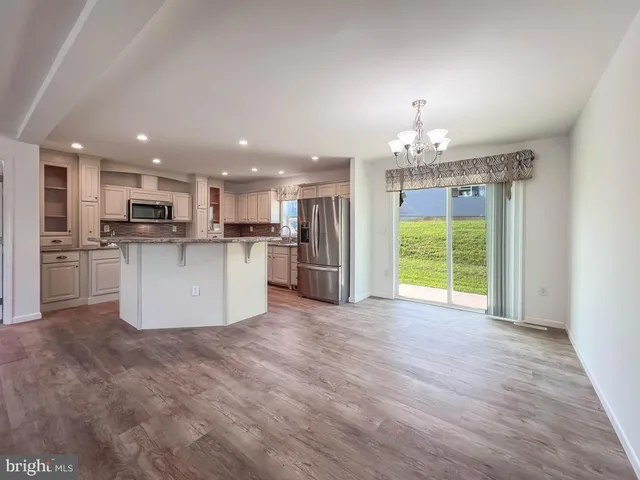 a view of a kitchen with a stove wooden cabinets wooden floor and a chandelier