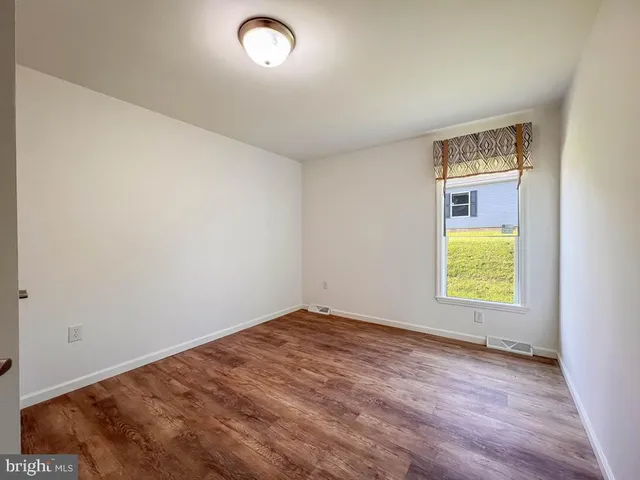 an empty room with a window and a dresser