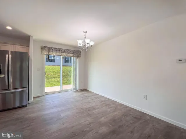 a view of an empty room with a window and kitchen view