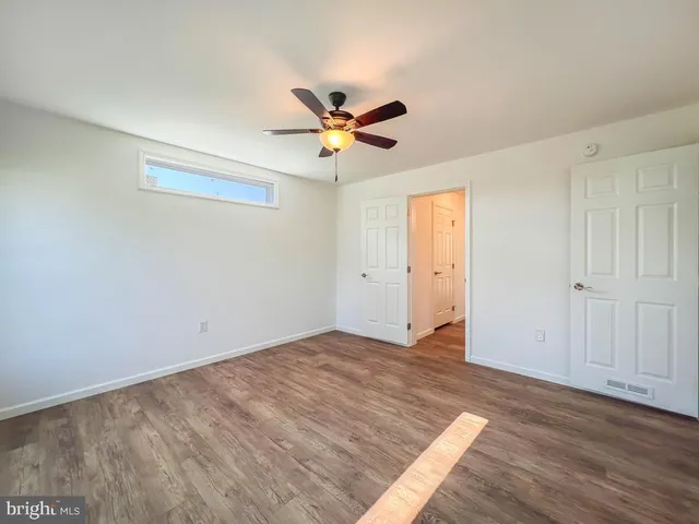 a view of empty room with wooden floor and ceiling fan