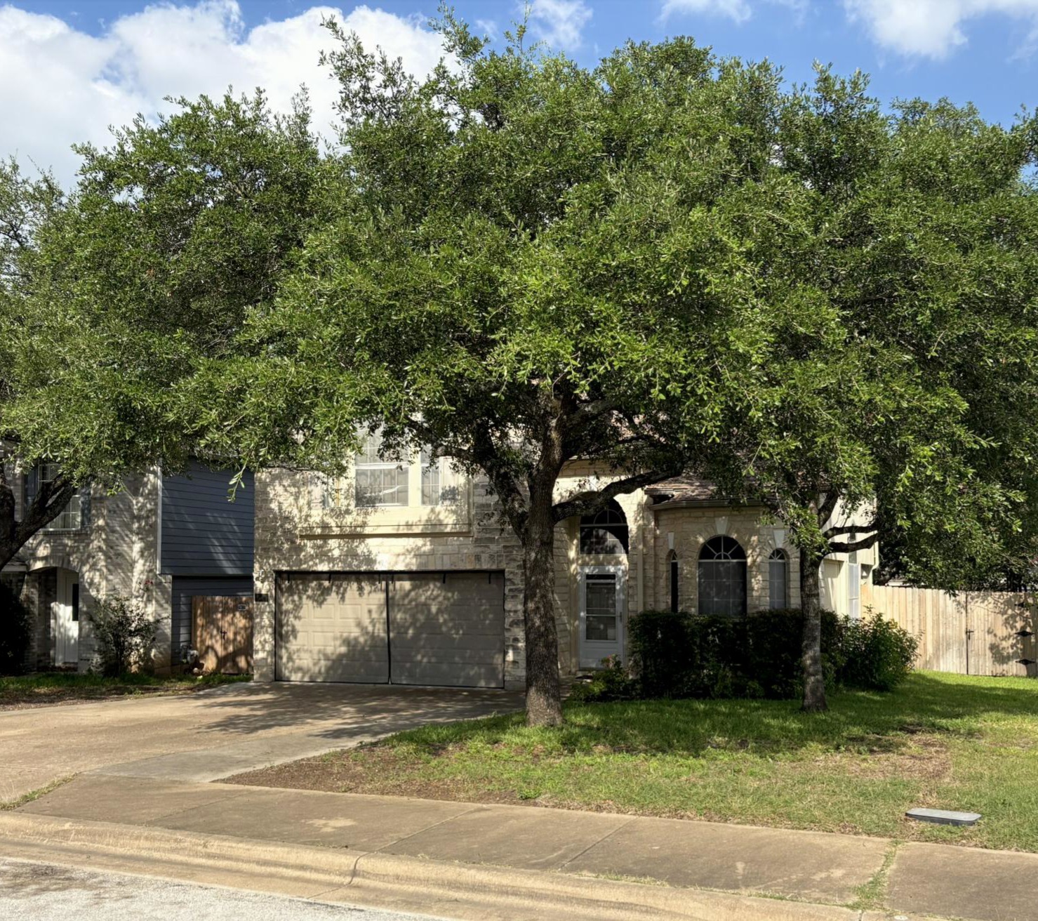 14707 Single Trace Austin, TX 78728 - Photo 2 of 17 Mature trees frame this home's stone and siding exterior, complemented by an attached garage and a concrete driveway.