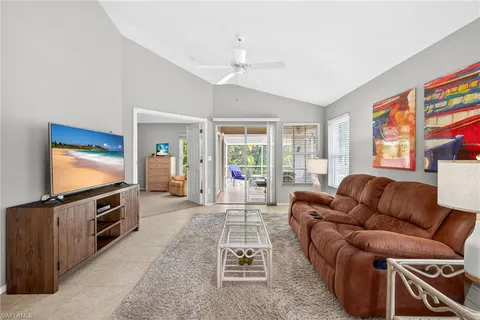 a living room with furniture a flat screen tv and a refrigerator
