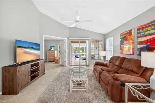 a living room with furniture a flat screen tv and a refrigerator