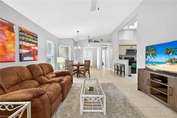 a living room with furniture a flat screen tv and kitchen view