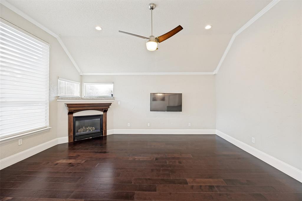 2100 Los Rios Boulevard Plano, TX 75074 - Photo 7 of 25 Vaulted ceiling room featuring dark wood-finish flooring, a corner-set fireplace with a wood mantle and stone top, and recessed lighting