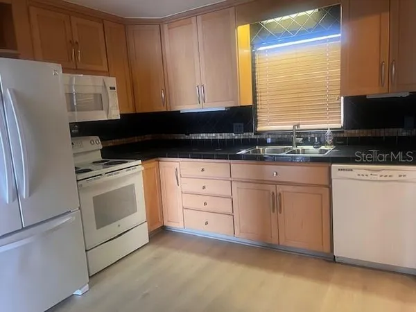a kitchen with granite countertop white cabinets and white appliances