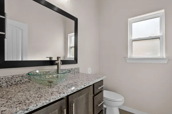 a bathroom with a granite countertop sink and a toilet