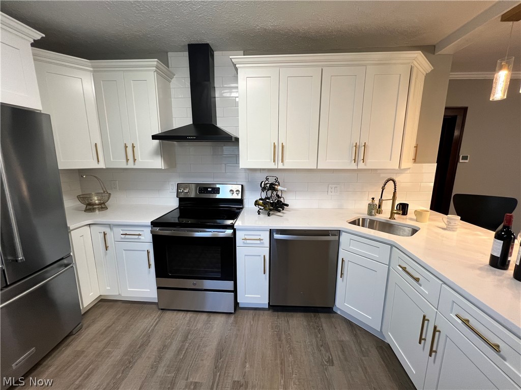 4523 Maplecrest Avenue Parma, OH 44134 - Photo 8 of 31 Kitchen with stainless steel appliances, wall chimney range hood, hardwood / wood-style flooring, and white cabinets