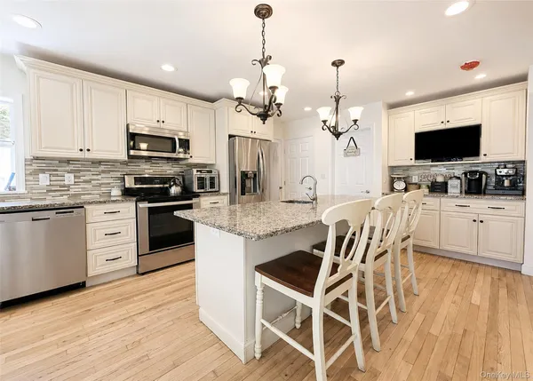 a kitchen with stainless steel appliances kitchen island granite countertop a stove top oven a sink a dining table and chairs with wooden floor