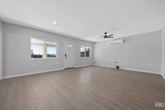 a view of an empty room with a window and wooden floor