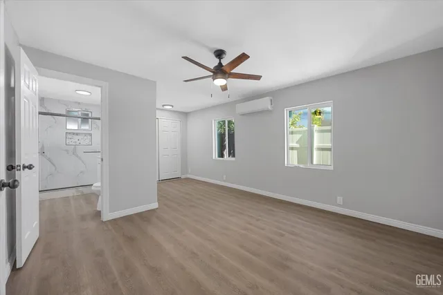 an empty room with wooden floor ceiling fan and windows