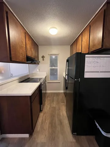 a kitchen with a sink a refrigerator and wooden cabinets