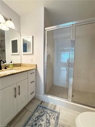 a bathroom with a granite countertop sink mirror and shower