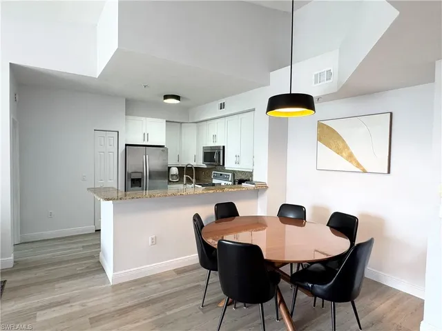 a kitchen with stainless steel appliances a dining table chairs and wooden floor