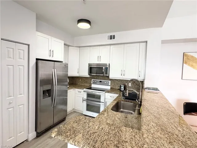 a kitchen with granite countertop a refrigerator stove microwave and sink