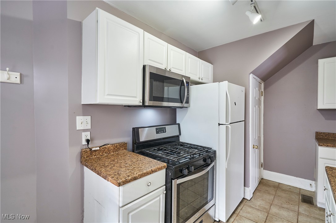 2152 Middlefield Road Cleveland, OH 44106 - Photo 12 of 50 Kitchen with white cabinetry, rail lighting, dark stone countertops, and appliances with stainless steel finishes