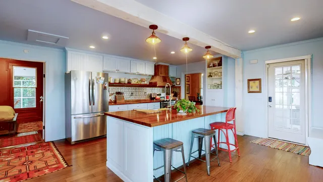 a kitchen with stainless steel appliances granite countertop a refrigerator a sink dishwasher a dining table and chairs with wooden floor