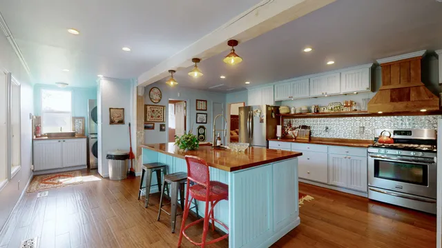 a kitchen with stainless steel appliances granite countertop a refrigerator a stove top oven a sink dishwasher and white cabinets with wooden floor
