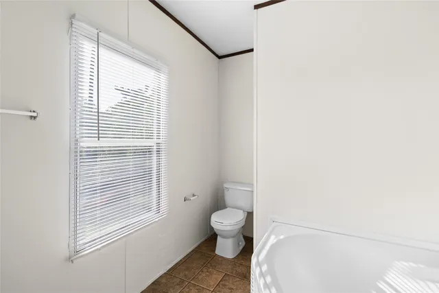 a bathroom with a granite countertop toilet a sink and a window