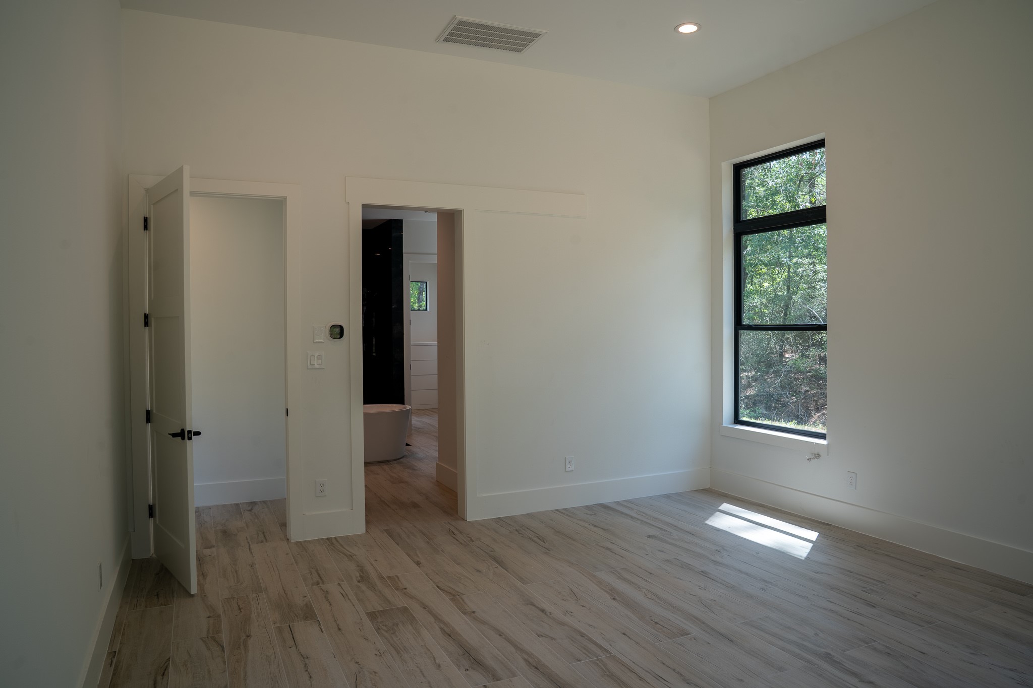 343 Sundog Road Huntsville, TX 77340 - Photo 18 of 37 Primary bedroom features 12-foot ceilings and the abundance of natural light provided by the large windows, creating a spacious and inviting atmosphere.