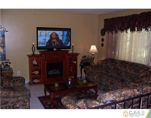 69 Morningside Road Colonia, NJ 07067 - Photo 8 of 25 a living room with furniture a fireplace and a flat screen tv