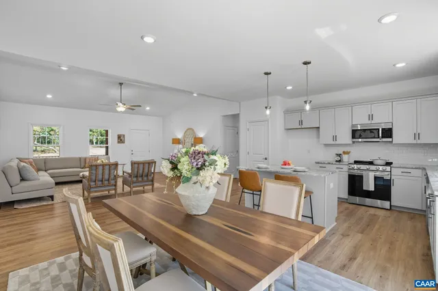 a kitchen with stainless steel appliances granite countertop a sink stove and white cabinets with wooden floor