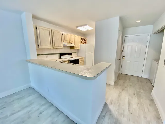 a kitchen with kitchen island granite countertop a sink cabinets and wooden floor