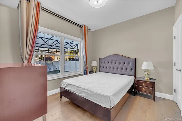 a bedroom with a bed table and a large mirror on the dresser